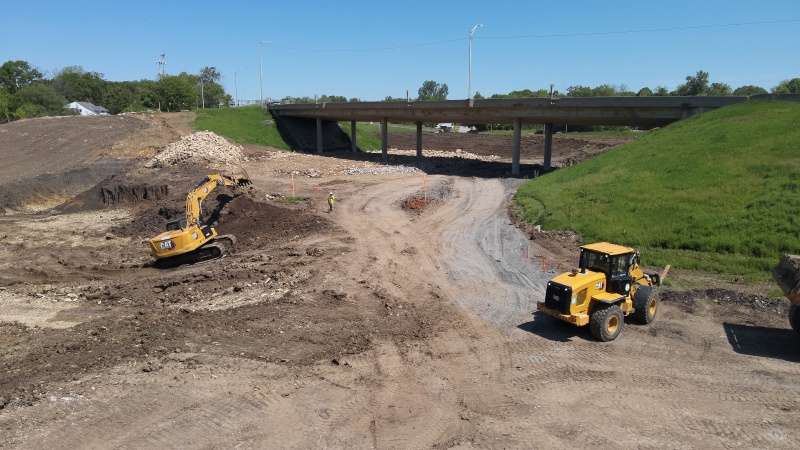 Excavator and other equipment moving dirt near an interstate bridge